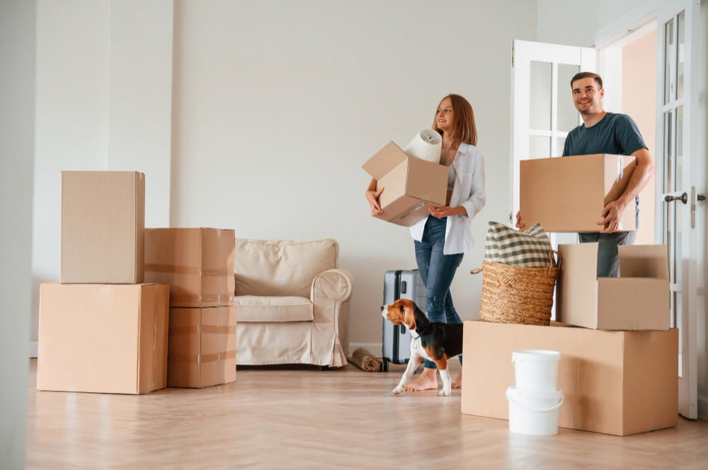 Un jeune couple et leur chien au milieu des cartons dans leur nouvel appartement, idéal pour estimer le prix déménagement Paris.